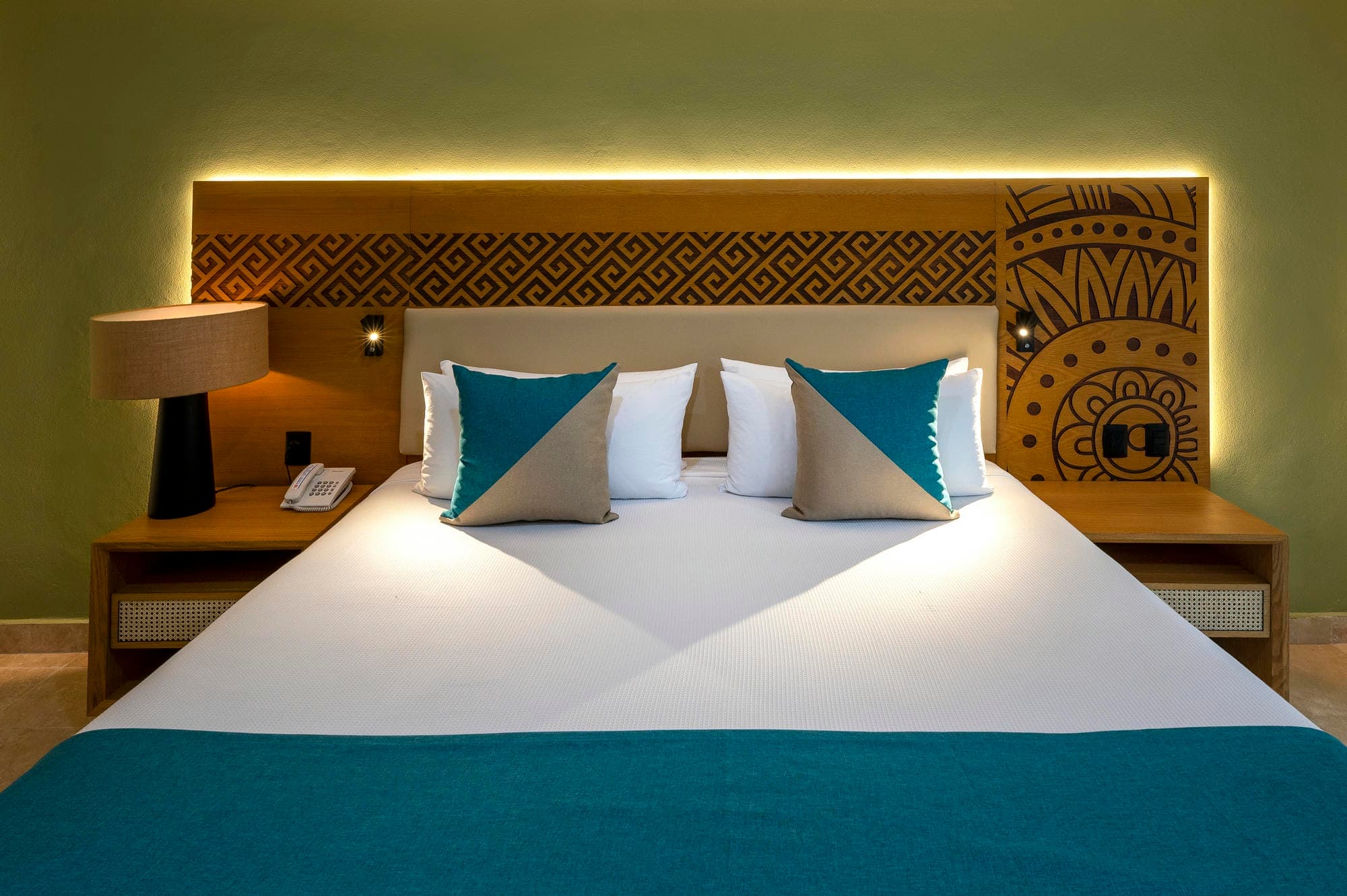Bed met blauw beddengoed en verlicht hoofdbord